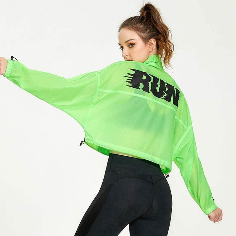 Woman wearing neon green sports jacket with RUN print, showcasing fitness fashion. Perfect for running and training.